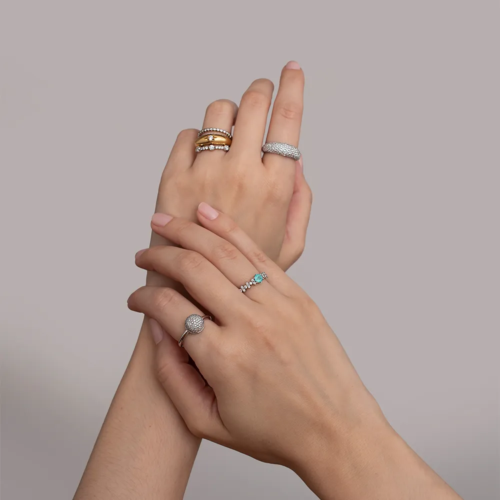 mãos com mix de anéis com diamantes e turmalina paraíba